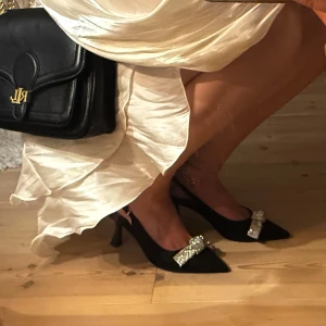 Svarta klackar - ‼️Endast använda en gång!, då jag köpte dem i våras 2025 i sista sekunden till en fest, men som egentligen var för små för mig.                                                             Säljer ett par svarta klackar från Tiamo i storlek 39. 👠Skorna har spetsig tå, låg klack och en snygg rosett. Remmen runt hälen ger extra support och de är tillverkade i mocka-look.                                             Köpta för 799 på Scorett. Mer information gällande skorna finns på sista bilden.