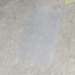 Telefon sugpropp - Smart mobilhållare med dubbelhäftande sugproppar som passar perfekt för alla typer av glatta ytor, såsom speglar och kakel. Hållaren fästs smidigt på baksidan av mobilen med hjälp av sugproppar. Tack vare att den har sugproppar på båda sidor kan du enkelt ta bort den från mobilen när den inte längre behövs. De smarta sugpropparna gör det möjligt att placera telefonen var du vill och sedan enkelt flytta eller ta bort den när du är klar.