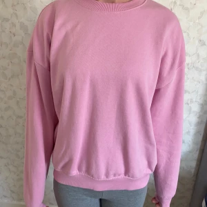 Rosa sweatshirt från 157, XS - Mjuk och skön rosa sweatshirt från 157 i storlek XS. Tröjan har rund hals, ribbade muddar och en loose passform. Perfekt för chill dagar och enkel att matcha med jeans eller leggings. Materialet är bomull och polyester för extra komfort.