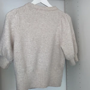 Beige stickad tröja från H&M - Säljer en beige stickad tröja från H&M i . Tröjan har korta, puffiga armar. Säljer för 90kr. Ursprungspris 299kr.