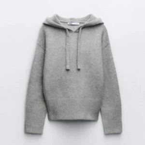 Grå stickad hoodie med huva - Mysig grå/brun stickad hoodie från Zara med ribbade muddar och nederkant. Tröjan har huva med snörning och långa ärmar, perfekt för chill dagar. Materialet är mjukt och ger en skön känsla. Enkel och stilren design som funkar till jeans eller mjukisbyxor. Knappt använd. Bra skicka, smått nopprig från nära håll.