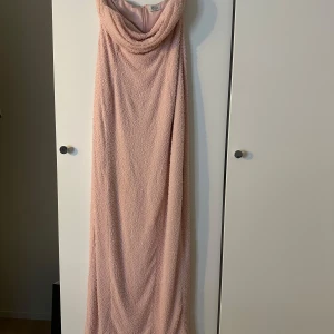 Ljusrosa axelbandslös långklänning - Supersnygg ljusrosa långklänning från Oh Polly som endast är använd en gång med axelbandslös design och draperad överdel. Klänningen har en figurnära passform och är täckt av små pärlliknande detaljer som ger en lyxig känsla. Perfekt för dig som vill sticka ut med en elegant look.