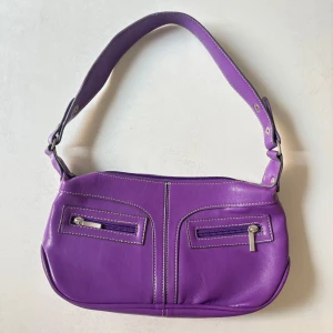 Lila axelväska från Franco Rino - Bra skick!! Så fin och unik lila axelväska från Franco Rino i skinn med bred axelrem och två dragkedjefickor framtill. 