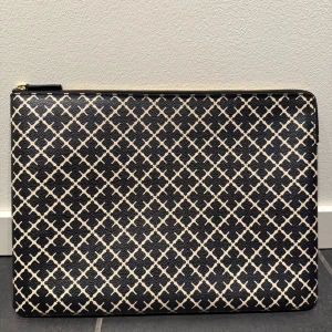 Ivy Laptop case 13” i Black från By Malene Birger - Snyggt och stilrent datorfodral från By Malene Birger i storlek 13 (36 x 26 cm) i färgen Black. Datorfodralet har en dragkedja i guld och en insida i en mjuk rosa nyans, samt en innerficka. Fodralet är använt mycket, men är fortfarande i bra kvalité. Enbart enstaka slitage (se sista bilderna)