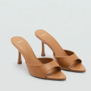 Bruna klackpumps från Mango - Snygga bruna pumps från MNG med öppen tå och spetsig form. Skorna har en hög klack och är tillverkade i slätt syntetmaterial som ger en clean och modern look. Perfekt för dig som gillar minimalistisk stil och vill ha ett par statement heels.