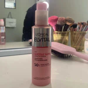 L'Oréal Elvital Glycolic Gloss Serum - Säljer en L'Oréal Paris Elvital Glycolic Gloss leave-in serum, 150 ml. Flaskan är rosa med silvrig etikett och pumpfunktion. Serumet innehåller 14% gloss complex och är berikat med glykolsyra för extra glans. Perfekt för att ge håret en snygg, glansig finish.