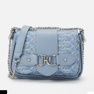 Blå axelväska Juicy Couture - Slutsåld snygg ljusblå axelväska från Juicy Couture med silverfärgad kedja och JC-logga framtill. Väskan har ett coolt mönster med Juicy-tryck, flera fack med dragkedja och en matchande liten plånbok. Väskan är endast använd en gång. Nypris: 1050kr.