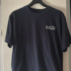 Mörkblå Notre Yacht Club t-shirt - Snygg mörkblå t-shirt från Notre med tryck på både bröstet och ryggen. Framsidan har en liten vit text med 'Yacht Club', medan ryggen har ett stort, iögonfallande tryck med 'NOTRE' och marina detaljer. Klassisk passform och rund hals, perfekt för en chill och sportig look.