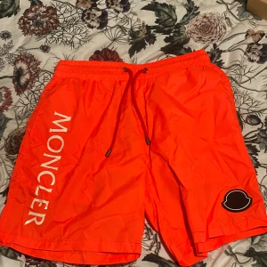Röd badbyxa från moncl3r - Shorts från Moncler i röd färg med stor logotyp längs benet och snörning i midjan. Perfekt för sommaren med sol och bad.