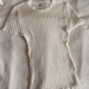 Vit ribbad topp från Zara - Säljer min supersnygga vita ribbade topp från Zara. Tröjan är tunt, lätt och är gjord av ett transparent material (se bild 3) som ger en cool look. Säljes då den inte kommer till användning. Tröjan är i bra sick men lite nopprig. Hör av er vid intresse eller frågor.😊