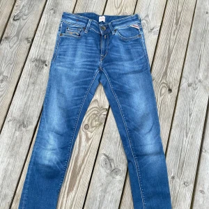 Blå jeansbyxor från Replay - 24/30 Snygga blå jeansbyxor från Replay med klassisk femficksdesign och gul kontrastsöm på bakfickorna. Byxorna har normal passform och raka ben. Priset kan diskuteras