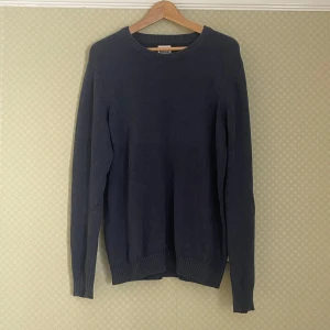Mörkblå stickad tröja från Dobber - Säljer en mörkblå stickad tröja från Dobber i storlek Large. Tröjan har rund halsringning, långa ärmar och ribbade muddar vid ärmslut och nederkant. Perfekt och enkel att matcha med olika outfits.