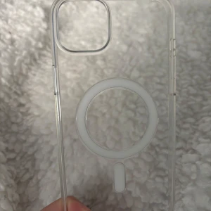 Transparent MagSafe mobilskal från Apple - Säljer ett genomskinligt mobilskal från Apple med MagSafe-funktion. Skalets design är stilren och minimalistisk, perfekt för dig som vill visa upp din mobil samtidigt som du skyddar den. Passar iPhone och har rund MagSafe-ring på baksidan. Originalpris: 695kr