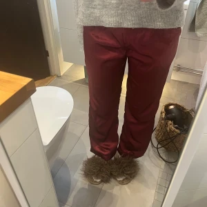 Vinröda pyjamas/mjukisbyxor med resårmidja - Säljer ett par vinröda pyjamas/mysbyxor med rak passform och resår i midjan. Byxorna har en enkel design utan synliga detaljer och är tillverkade i ett siden material.