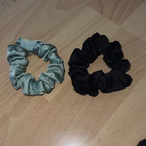2-pack scrunchies i satin, svart & grön - Säljer två snygga scrunchies i satin – en i klassiskt svart och en i ljusgrön nyans. 
