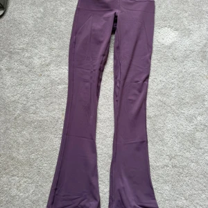 Lila bootcut leggings från Lululemon - Säljer ett par lila leggings från Lululemon med bootcut-ben och hög midja. De är tillverkade i ett mjukt och stretchigt syntetmaterial som passar perfekt för träning eller chill. Snygg passform med utsvängda ben. Modell: 	 lululemon Align™ High-Rise Mini-Flare Pant *Regular