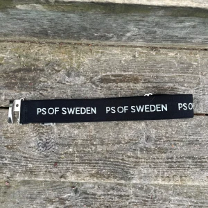Svart bälte från PS of Sweden - Snyggt svart skärp från PS of Sweden med tydlig vit logga tryckt längs hela bältet. Bältet har ett silvrigt spänne och är gjort i ett slitstarkt material. Perfekt accessoar för att lyfta din outfit.  Bara använd fåtal gånger då jag inte har så många ridbyxor med öglor i, därav väldigt fint skick🤩