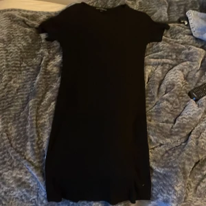 Svart ribbad klänning XOXO friends - En svart, ribbad kortklänning från XOXO friends. Klänningen har korta ärmar, rund halsringning och är figurnära i modellen. Tillverkad i mjuk bomullsmix som känns skön mot huden. Enkel och stilren design som är lätt att matcha. Använd en gång.