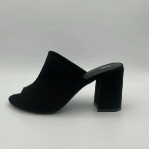 Svarta slip-in klackar från XIT - Säljer ett par svarta slip-in klackar från XIT med öppen tå och bred klack. Skorna har en stilren design i mocka och passar perfekt till dig som vill ha en enkel men trendig look.