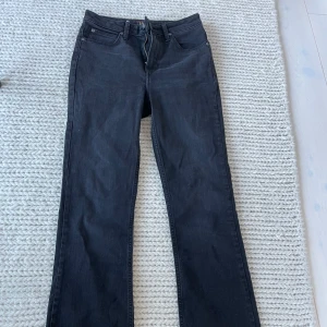 Svarta bootcut jeans från Lee - Säljer ett par svarta bootcut jeans från Lee. Klassisk femficksmodell med dragkedja och knapp framtill. Jeansen har hög midja och raka ben med lätt utsvängd bootcut. Perfekta till vardags för en stilren look.