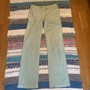 Ljusgröna mjukisbyxor från juicy couture - Snygga ljusgröna mjukisbyxor med raka ben och stora fickor både fram och bak. Byxorna har resår i midjan och är tillverkade i ett mjukt material som känns skönt mot huden. Perfekta för en chill och avslappnad stil.