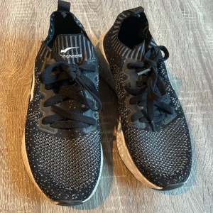 Svarta sneakers från Bagheera - Svarta sneakers från Bagheera med stickad ovandel och vita detaljer. Skorna har snörning, rund tå och en vit, mönstrad sula. Lätta och flexibla med sportig känsla, perfekta för dig som gillar en aktiv stil.