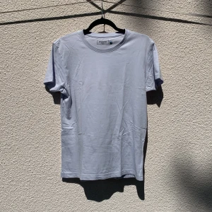 Ljusblå t-shirt från Dressmann - Klassisk ljusblå t-shirt från Dressmann i 100% bomull. Enkel design med rund halsringning och korta ärmar. Knappt använd.
