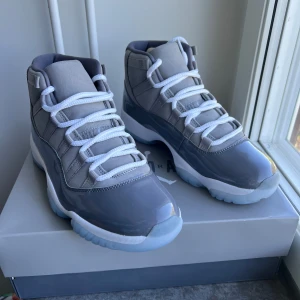 Air Jordan 11 Retro Medium Grey - Säljer ett par Air Jordan 11 Retro i färgen medium grey. Skorna har en hög siluett, vit sula och grå ovandel i både blankt och matt material. Klassisk snörning och ikonisk design. Perfekta för dig som gillar sneakers med stilren look.