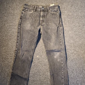 Svarta jack and Jones jeans - Snygga svarta jeans med och klassiska fem fickor. Jeansen har en smal passform och är tillverkade i ett stretchigt denimtyg som sitter tajt längs benen. Perfekta för en clean och stilren look.