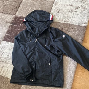 Svart Monclee Windbreaker - Skick 9/10, storlek 3/L men passar Mindre också. Givetvis autentisk, perfekt nu inför sommaren. säljer för endast 1499.