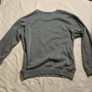 Grå basic sweatshirt - Enkel grå sweatshirt i mjuk bomull med rund hals och långa ärmar. Perfekt för chill dagar eller när du vill ha en clean och avslappnad look. Ribbad mudd vid ärmslut och nederkant för extra komfort.