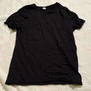 Svart t-shirt med vågig ärm - Enkel svart t-shirt med vågig ärm från UNIQ YOUNG med klassisk rund hals och korta ärmar. T-shirten har en rak passform och är tillverkad i mjukt material som känns skönt mot huden. Perfekt basplagg att matcha med jeans eller shorts.