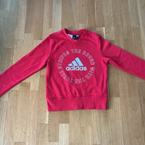 Röd långärmad Adidaströja - Tjena! Säljer en röd långärmad tröja från Adidas med stort vitt tryck på bröstet. Tröjan är mjuk och skön. Perfekt för dig som gillar sportig och avslappnad stil.