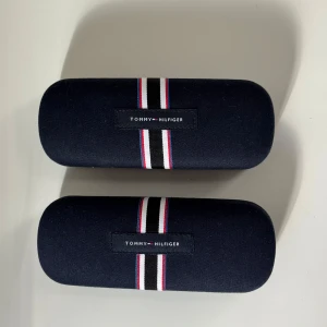 Tommy Hilfiger Fodral - Tommy Hilfiger glasögonfodral två styckna med väldigt hög kvalité, dom är knappt använda och är i färg marinblå Hittade ingen original förpackning eller kvitto  Du kan alltid köpa med ett par glasögon med fodralen så får du med allt på samma gång!