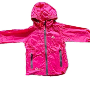 Rosa regnjacka med huva från Trespass Qikpac - Säljer en rosa regnjacka från Trespass Qikpac med huva och dragkedja framtill. Jackan är lätt, vattentät och andas, perfekt för blöta dagar. Förvaringspåse medföljer så den är enkel att ta med sig.. Barnjacka i storlek 104