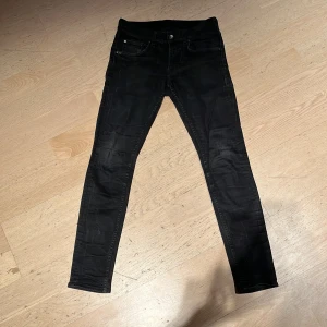 Svarta slim jeans från Tiger of Sweden - Snygga svarta slim fit jeans från Tiger of Sweden. Tillverkade i Italien med en stilren design och klassiska femficksdetaljer. Perfekta för en stilren look.