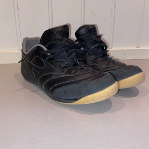 Mizuno Morelia svarta inomhusfotbollsskor - Svarta Mizuno Morelia futsal/inomhusfotbollsskor. Använda ca 10-15 gånger. Säljer de pga att de är lite för stora. De är i storlek 42 men passar bättre för storlek 41/41,5 skulle jag säga! Nypris 1199!