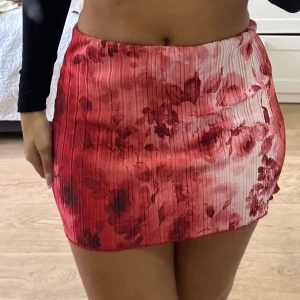 Röd blommig kjol från PrettyLittleThing - Superfin kort kjol från PrettyLittleThing i röd och rosa ton med blommigt mönster. 