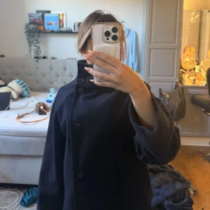 Blå skepparkavaj i ull - Säljer min marinblåa kappa ifrån Ginatricot då den ej kommer till användning eftersom jag har en liknande jag föredrar. Använd under en höst men är i mycket bra skick utan synliga defekter. Går gärna ner i pris vid snabbaffär. Hör av dig vid frågor ☺️