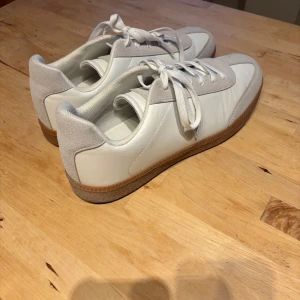 Vita sneakers från Sandö  - Stilrena vita sneakers från Sandö. Använda endast en promenad. Som nya! Klassisk design med snörning och platt sula i gummi. Perfekta för en clean och fräsch look, passar till allt.