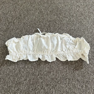 Vit bandeau tubtopp från H&M - Supersöt vit bandeau tubtopp från H&M i storlek XS. Toppen har volangkant och smockad resår både upptill och nedtill samt snörning i ryggen. Endast testad då jag inte gillade passformen men lappen är tyvärr av då jag fick den i present utan lapp så kunde ej lämna tillbaks. 