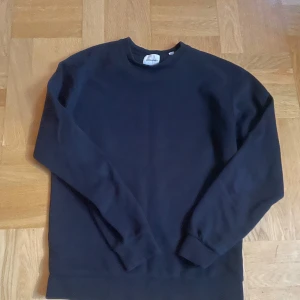 Mörkblå sweatshirt från Jack&Jones - En enkel och stilren mörkblå sweatshirt från Jack and Jones. Tröjan har rund hals, långa ärmar och ribbade muddar vid ärmslut och nederkant. Perfekt för chill dagar eller när du vill ha en clean look.