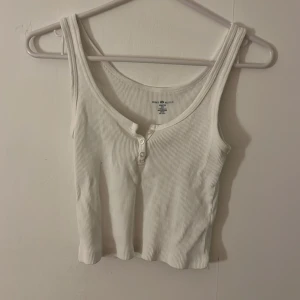 Vit crop top med knappar - Ett vitt kort linne med knappar från brandy.