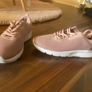 Rosa sneakers med vit sula - Snygga rosa sneakers med vit, chunky sula och mesh-överdel. Skorna har rund tå, snörning och är tillverkade i syntetmaterial med textilstruktur. Perfekta för en sportig och trendig look.