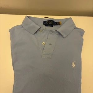 Ljusblå Polo Ralph Lauren piké  - Snygg ljusblå piké från Polo Ralph Lauren i slim fit-modell. Hör av dig vid frågor eller funderingar