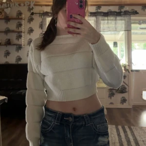 Vit croppad stickad tröja Shein - Säljer en vit croppad stickad tröja från Shein. Tröjan har långärmade puffiga ärmar och bred ribbstickning som ger en cool struktur. Perfekt till jeans eller kjol för en trendig look.