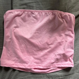 Ljusrosa bandeau tubtopp - Enkel och stilren ljusrosa bandeau tubtopp i mjuk bomull. Perfekt för varma dagar eller som lager under skjortor och jackor. Toppens elastiska kant upptill gör att den sitter på plats hela dagen.