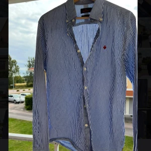 Randig skjorta från Morris, blå/vit - Snygg skjorta från Morris i blått och vitt med smala ränder. Klassisk krage, långa ärmar och knäppning framtill. Säljer för 249kr!‼️ skriv vid frågor