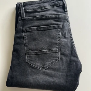 Svarta slim jeans från Jack & Jones - Snygga svarta jeans från Jack & Jones i modellen Slim/Glenn. Jeansen har en smal passform, klassisk femficksdesign och är tillverkade i stretchigt denim för extra komfort. Perfekt för dig som gillar en modern och stilren look.