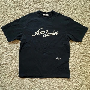 Acne Studios- knit oversized t shirt   - Svart t-shirt från Acne Studios med vit broderad logga på bröstet och mindre logga nedtill. Klassisk rund hals och korta ärmar. Tillverkad i mjuk bomull med snygg loose passform. Perfekt för dig som gillar stilrena och trendiga plagg. Den är knitted- dvs mer högkvalitativ och betydligt skönare än vanliga kortärmade tröjor- loggan är broderad och den har en oversized fit! Väldigt mysig och skön tröja